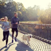 man and women run with their dog on a leash