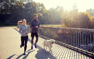 man and women run with their dog on a leash