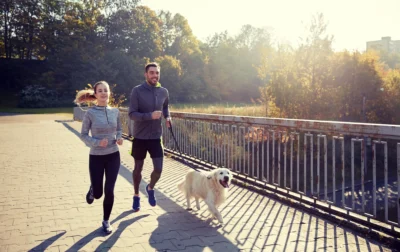 man and women run with their dog on a leash