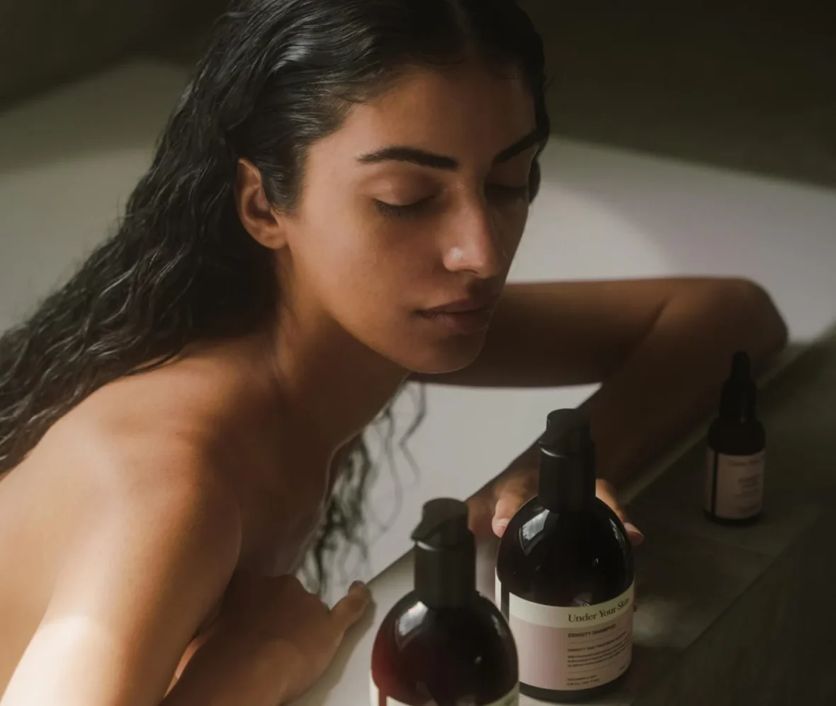 young woman in bath tub next to skincare products
