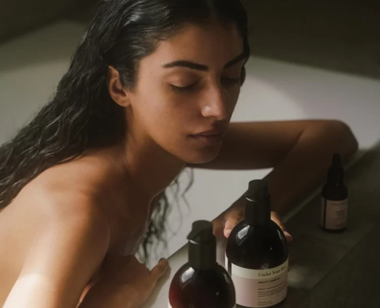 young woman in bath tub next to skincare products
