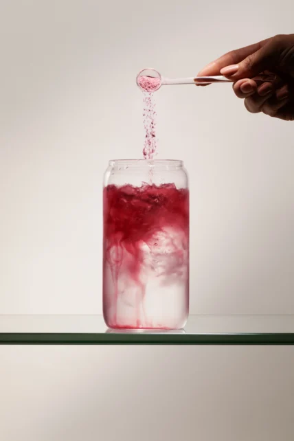 woman pours supplement powder into a drink