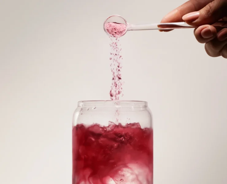 woman pours supplement powder into a drink