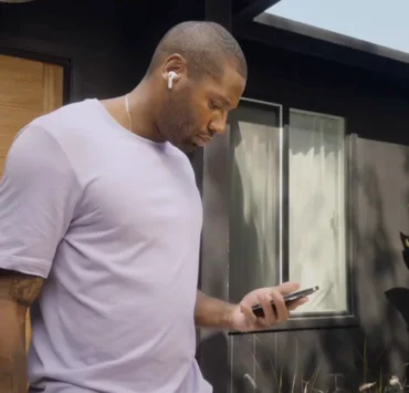 man looks at his phone while wearing AirPods