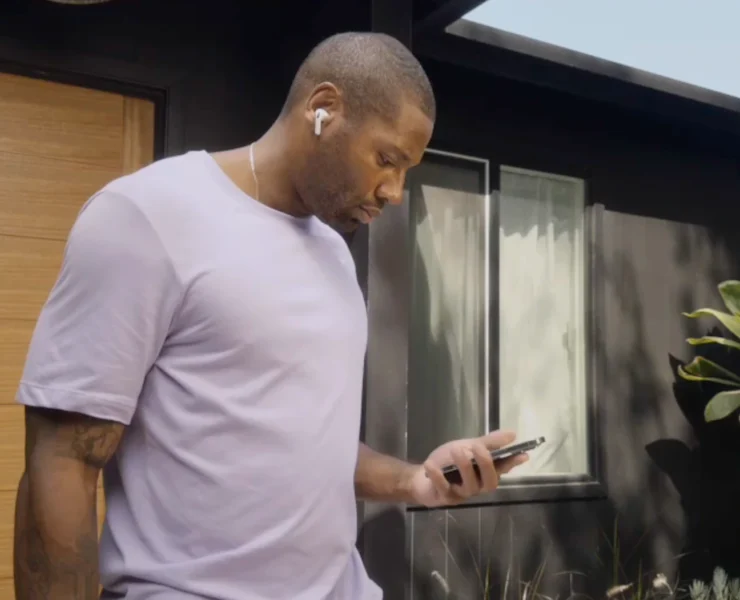 man looks at his phone while wearing AirPods