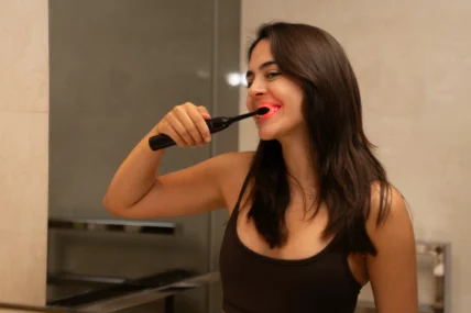 woman brushing her teeth with red light toothbrush
