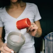 woman powers protein powder into a shaker bottle
