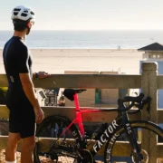 man stands next to a bike while overlooking the beach