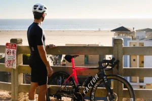 man stands next to a bike while overlooking the beach