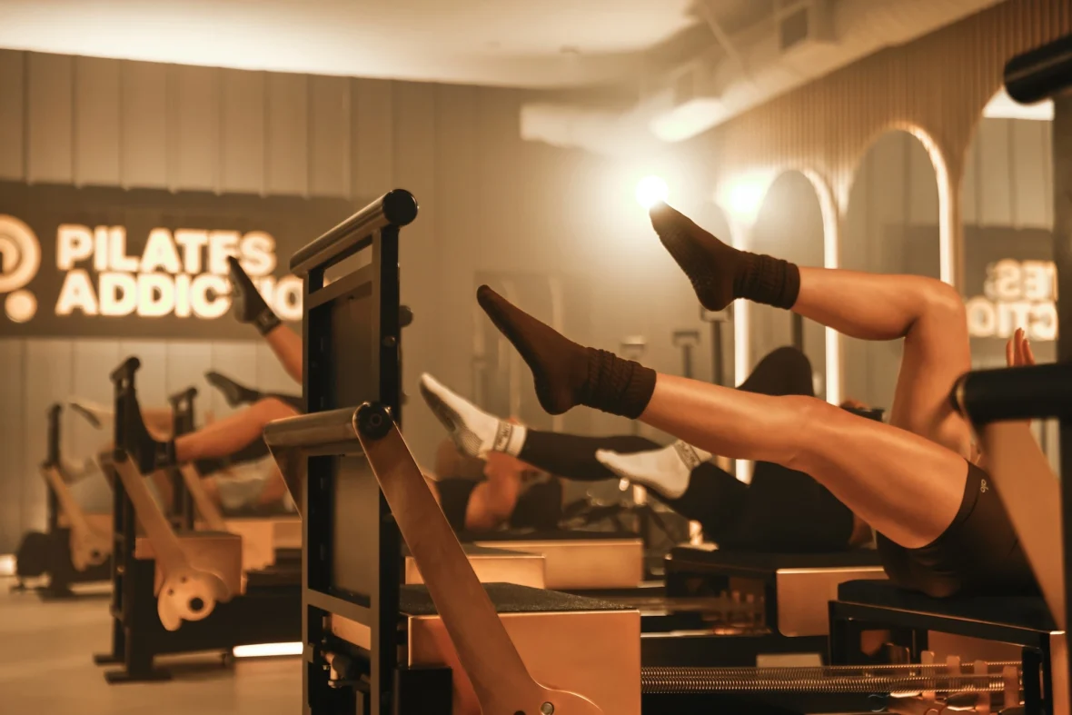 people on reformers inside a Pilates Addiction studio