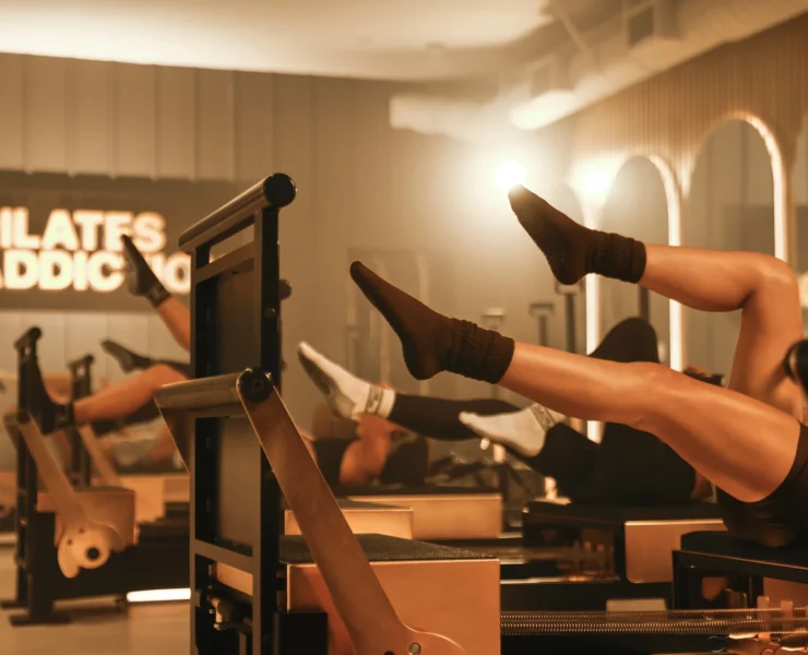 people on reformers inside a Pilates Addiction studio