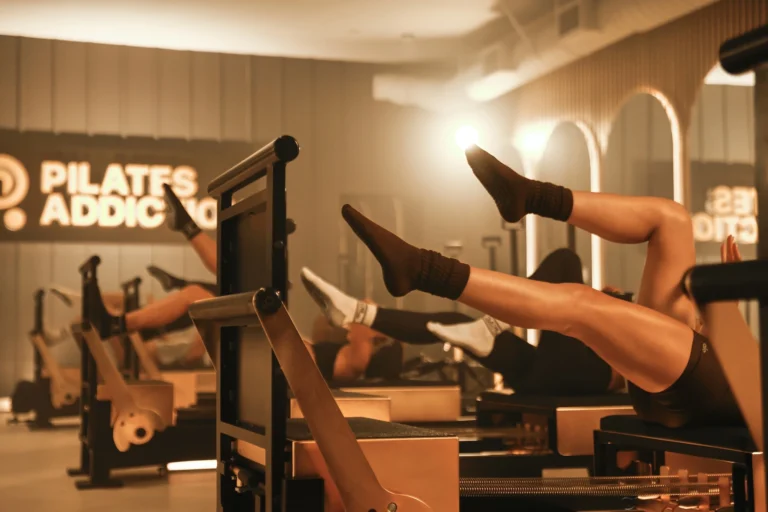people on reformers inside a Pilates Addiction studio
