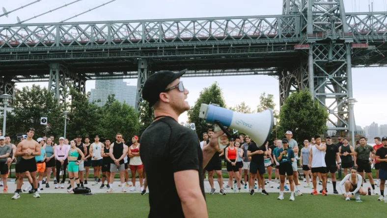 man holds a megaphone near a bridge in New York City