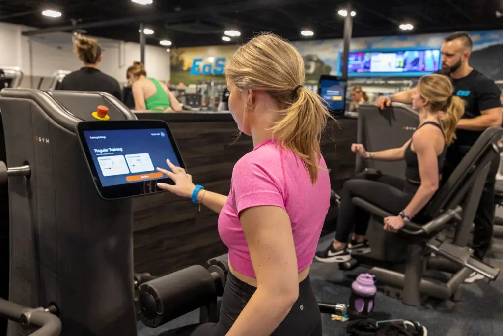 woman uses an EGYM machine at the gym