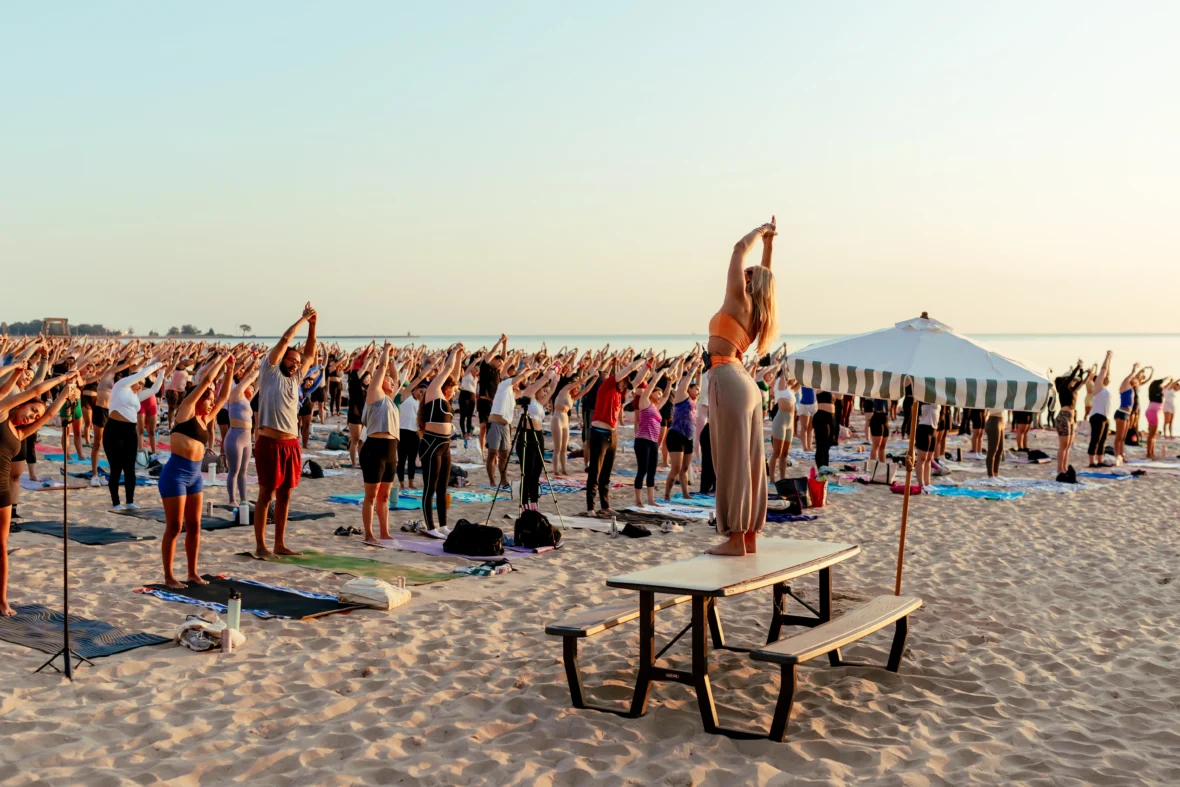 people participate in a yoga class on the beach