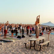 people participate in a yoga class on the beach