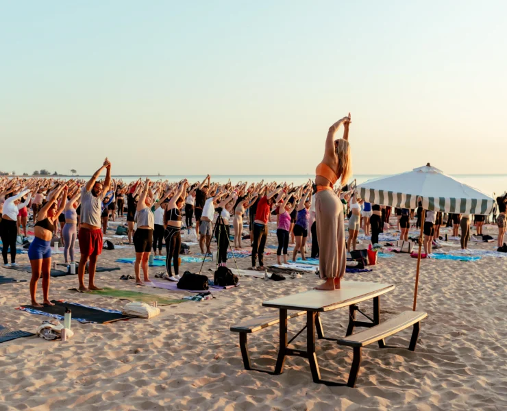 people participate in a yoga class on the beach
