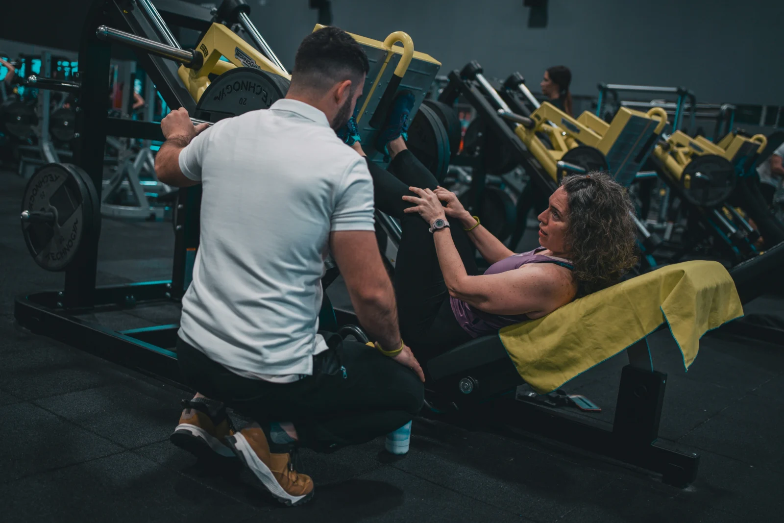 woman leg presses with her personal trainer