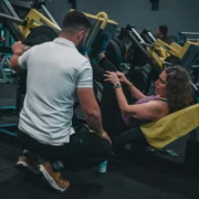 woman leg presses with her personal trainer