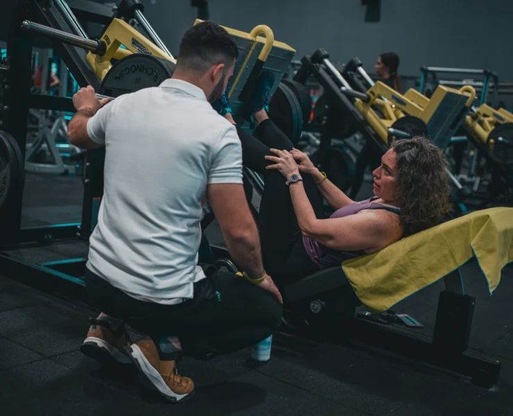 woman leg presses with her personal trainer