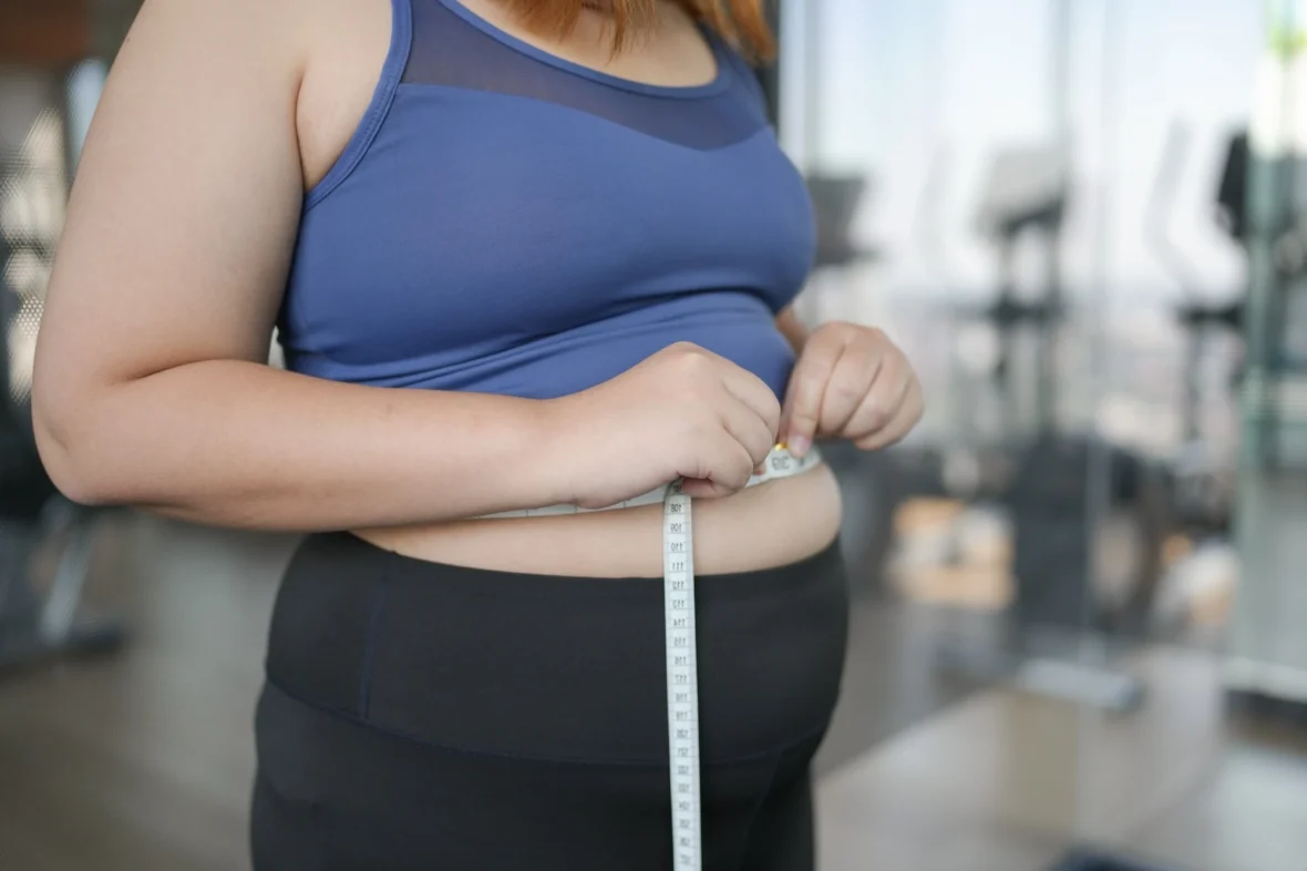 overweight woman measures her waist