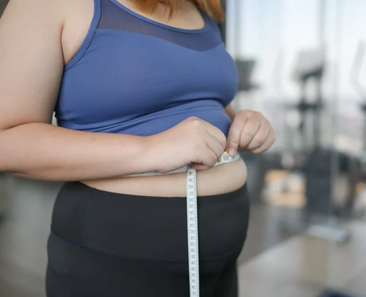 overweight woman measures her waist