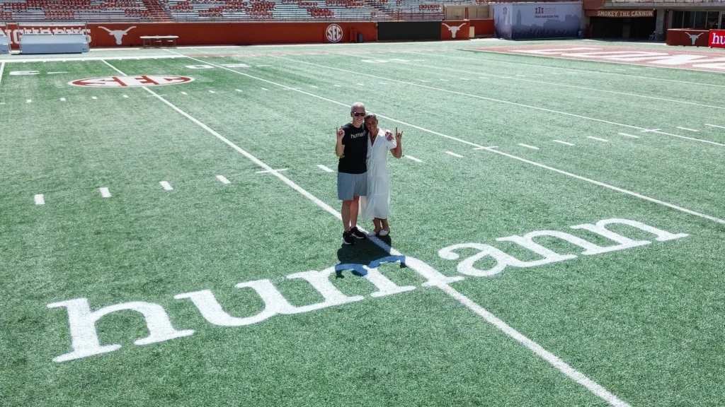 Joel Kocher and his wife on the field in front of a Humann logo