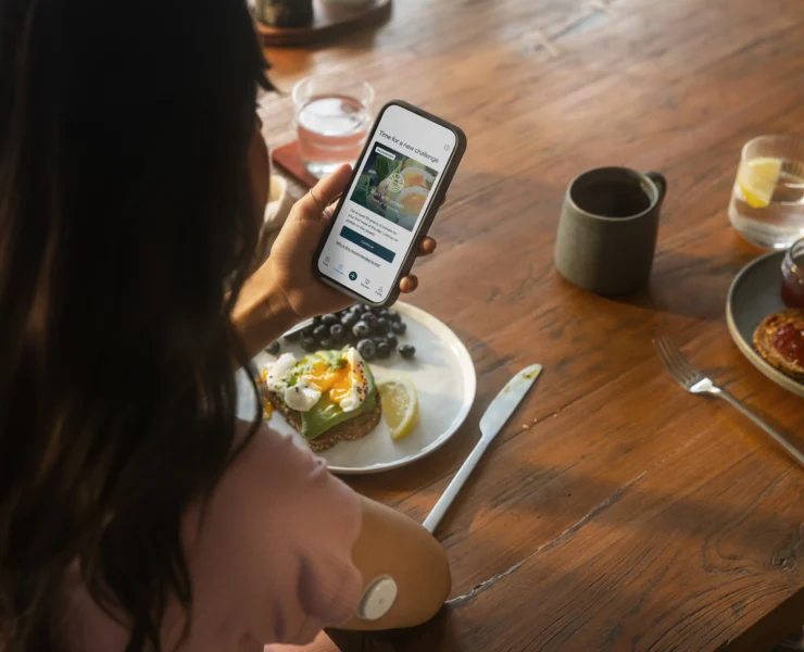 woman looks on her phone while eating