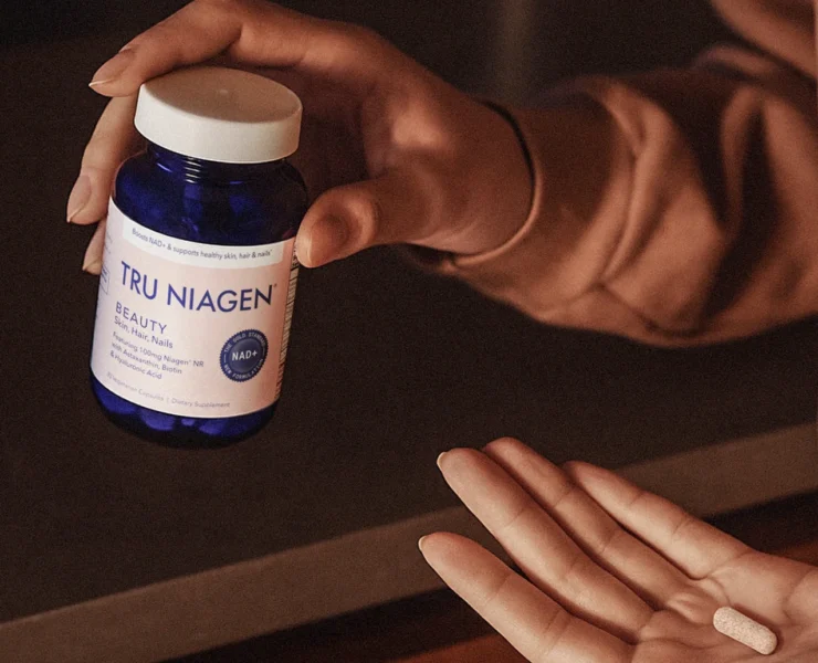 woman holds Tru Niagen Beauty pill