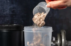 woman pours protein powder into a shaker bottle