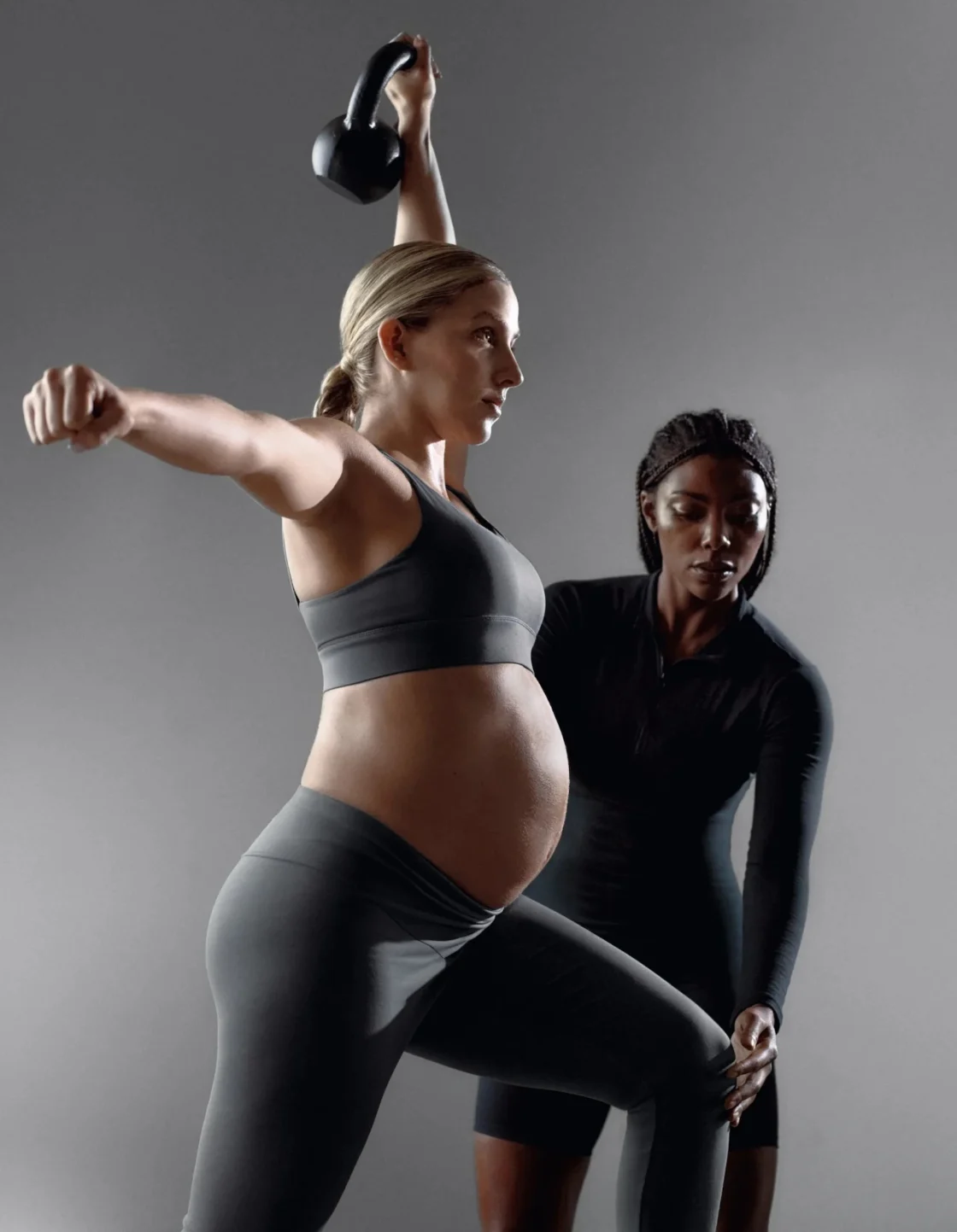 a pregnant woman works out with her trainer