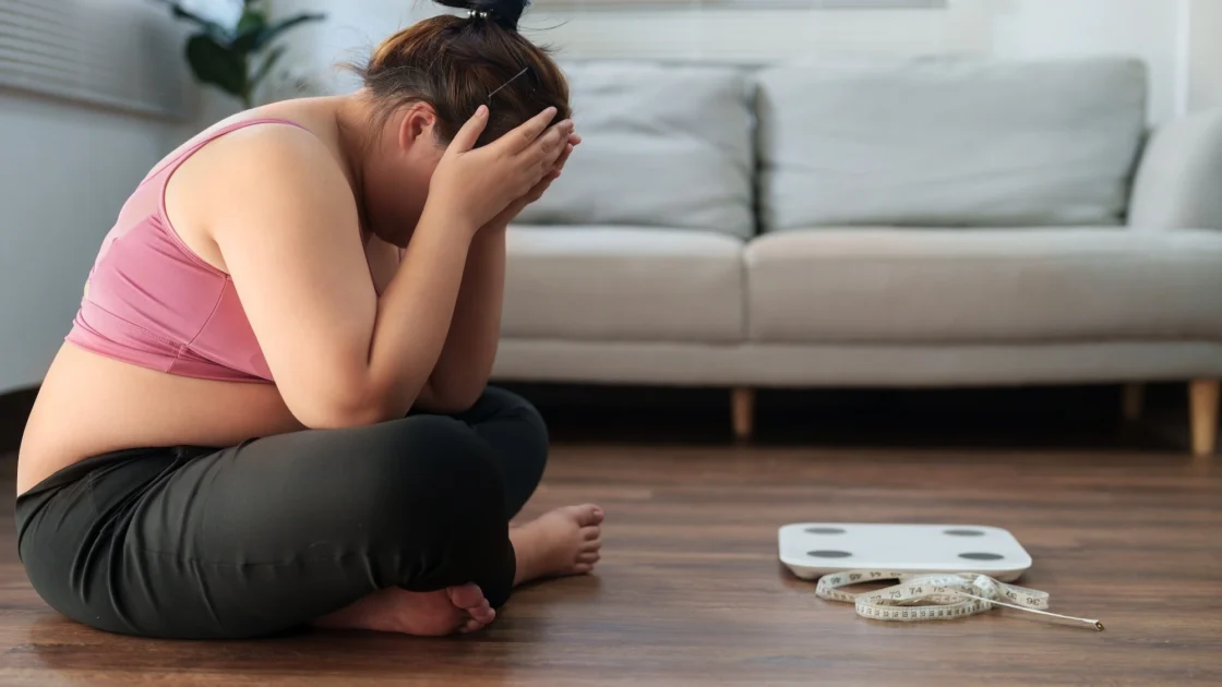 overweight woman is upset looking at the scale
