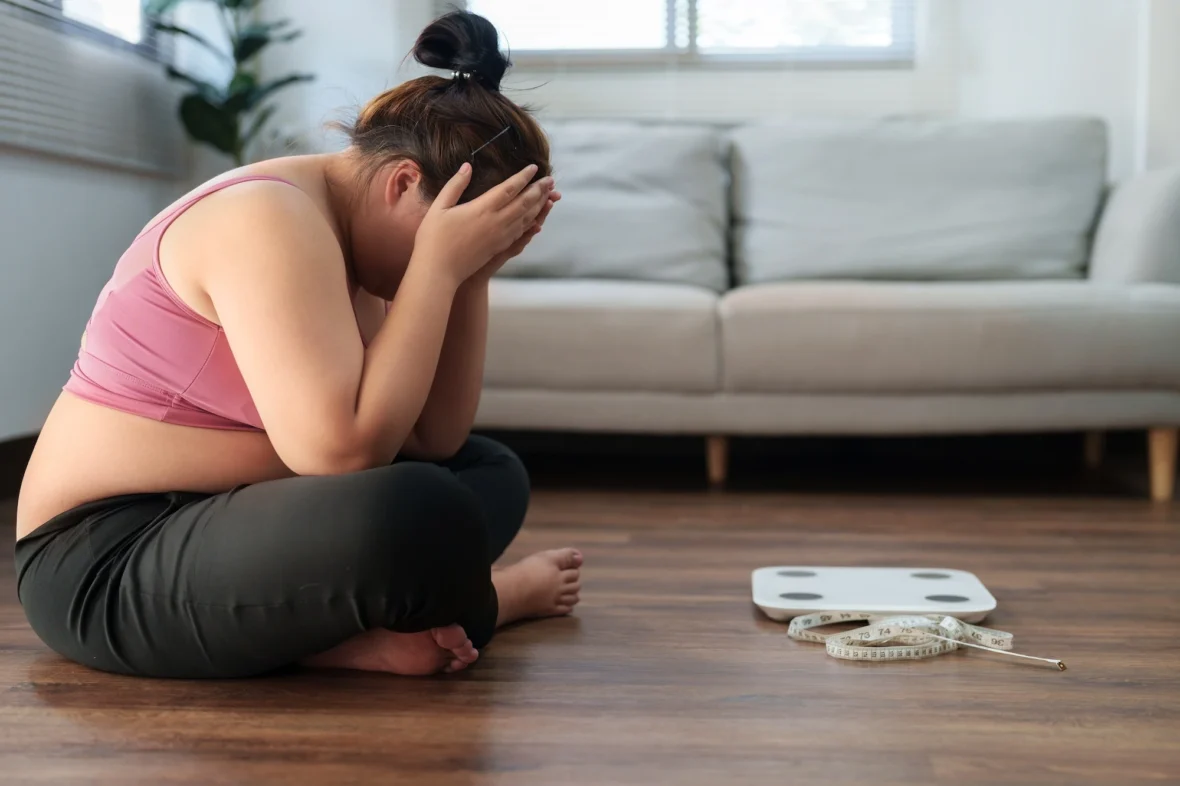 overweight woman is upset looking at the scale