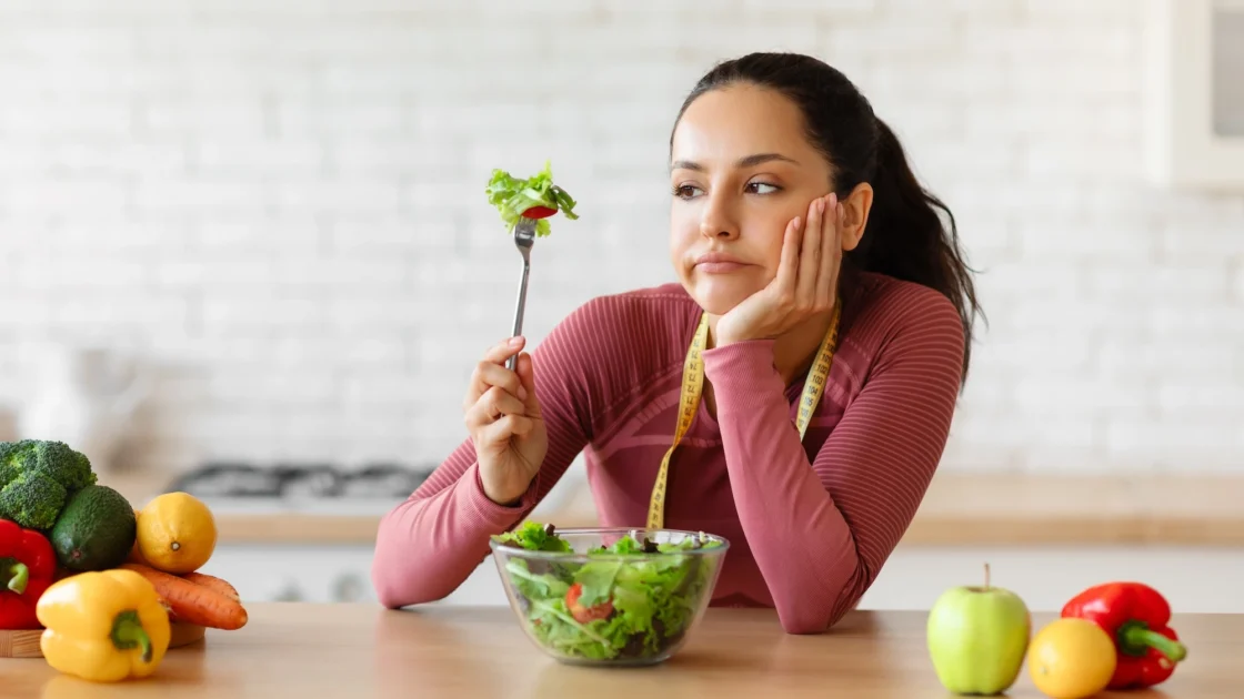woman looks exasperated eating vegetables