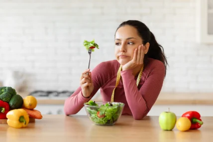 woman looks exasperated eating vegetables