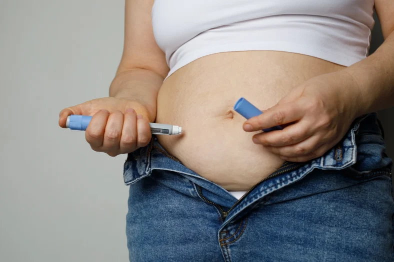 woman injects herself with a GLP-1 drug