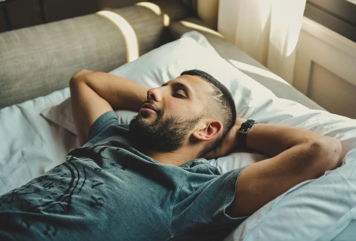 A man sleeping in bed with a watch on his wrist.