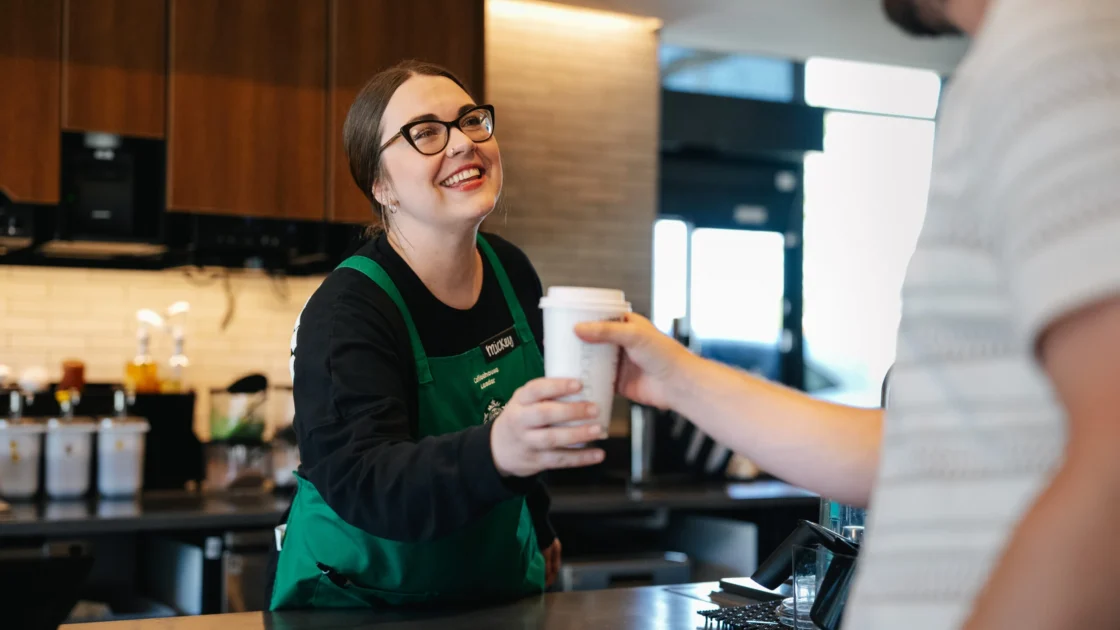 Starbucks barista hands a man a drink