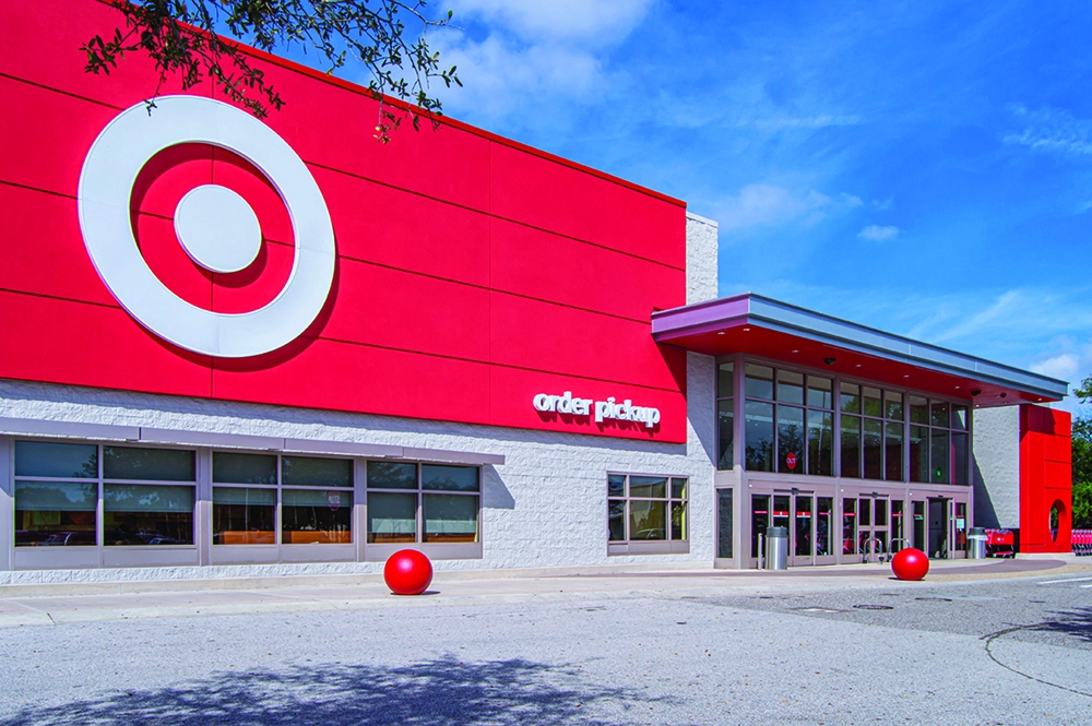 Exterior of a Target store with a bright red facade, large bullseye logo and an order pickup entrance under a blue sky.