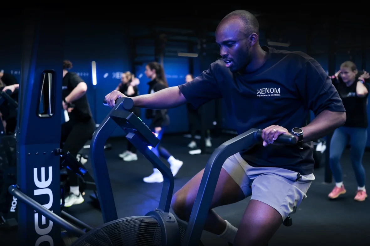 man uses an assault bike in a Xenom shirt
