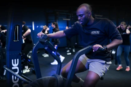 man uses an assault bike in a Xenom shirt