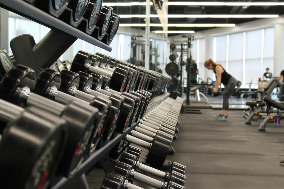 A woman in the background lifting weights at the gym.