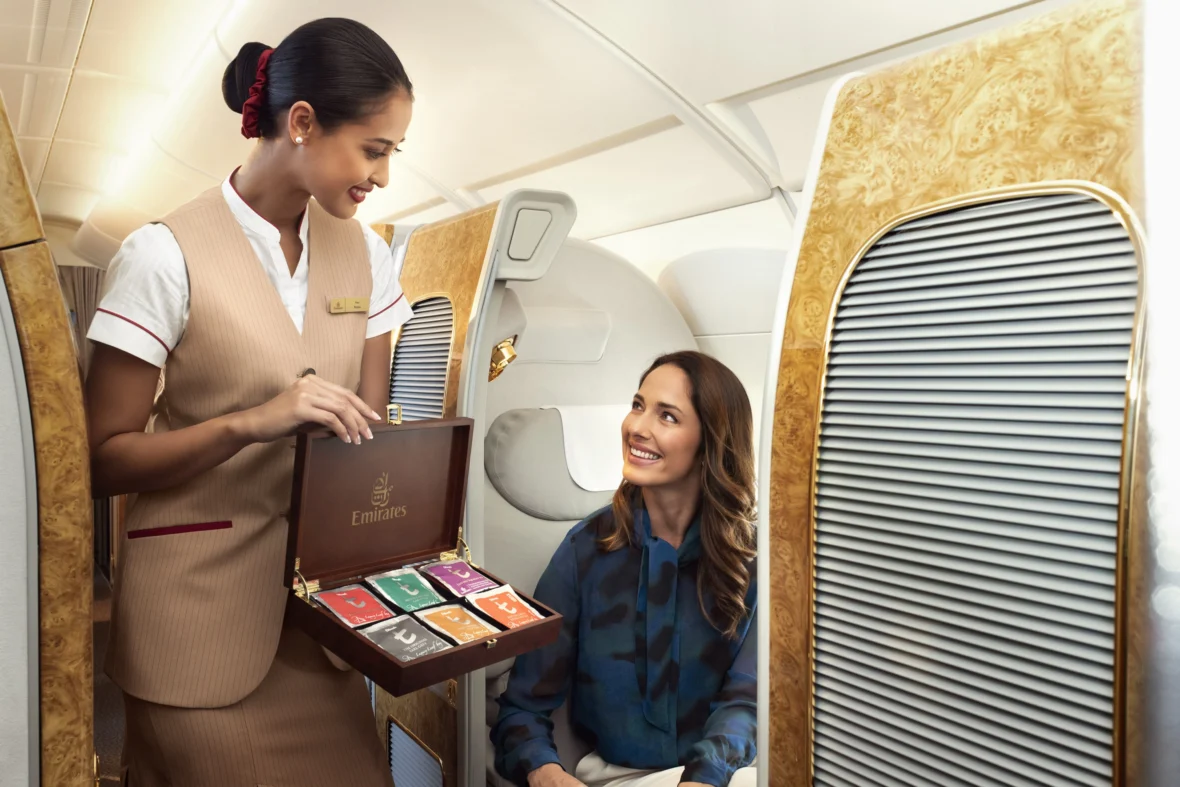 interior of Emirates airplane with flight attendant offering passenger tea options.