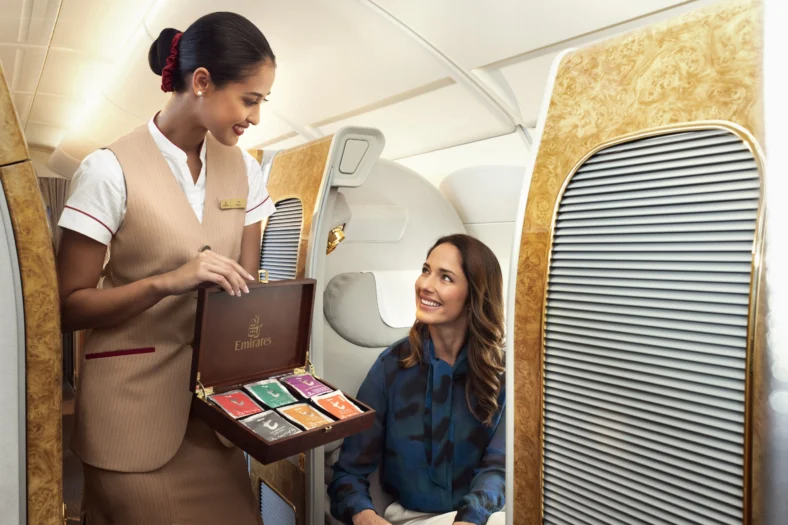 interior of Emirates airplane with flight attendant offering passenger tea options.