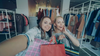 Two young women holding shopping bags while live-stream shopping.