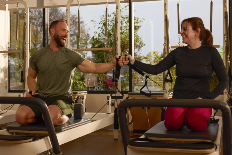 man and women on a Pilates reformers