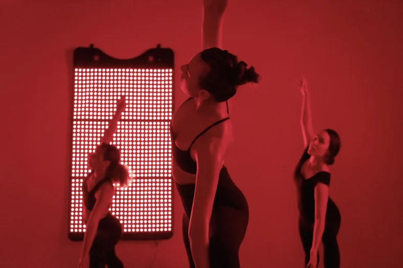 women doing yoga next to a red light heater
