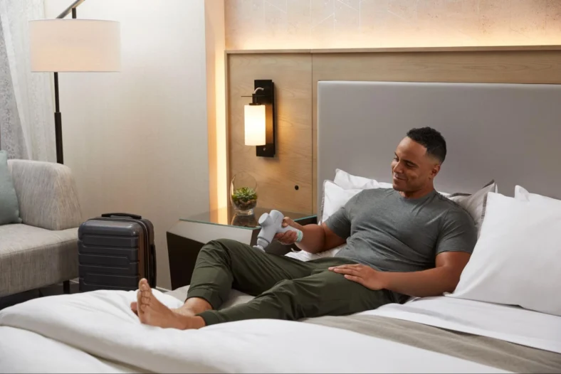 man on a bed uses a massage gun