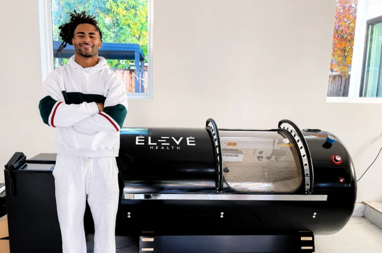 Fred Warner next to an Élev hyperbaric chamber