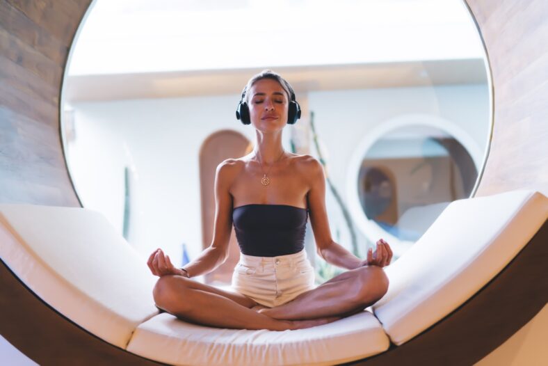 woman in headphones lounges on a circular bed